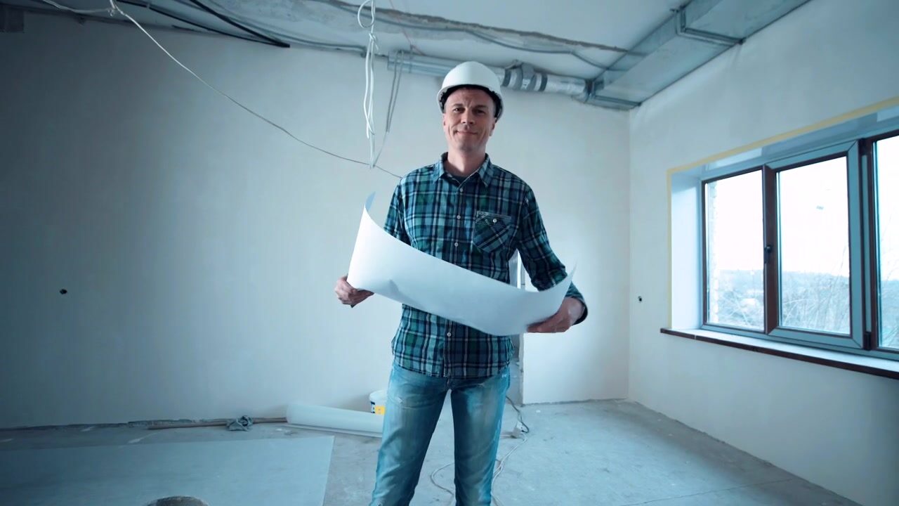 Engenheiro com capacete analisando o projeto dentro de um ambiente em reforma